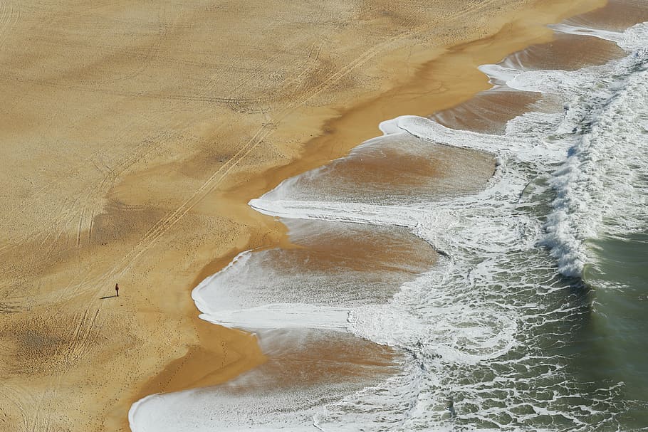 aerial photography of sea waves, bird's eye view of person standing on seashore while looking at splashing waves HD wallpaper