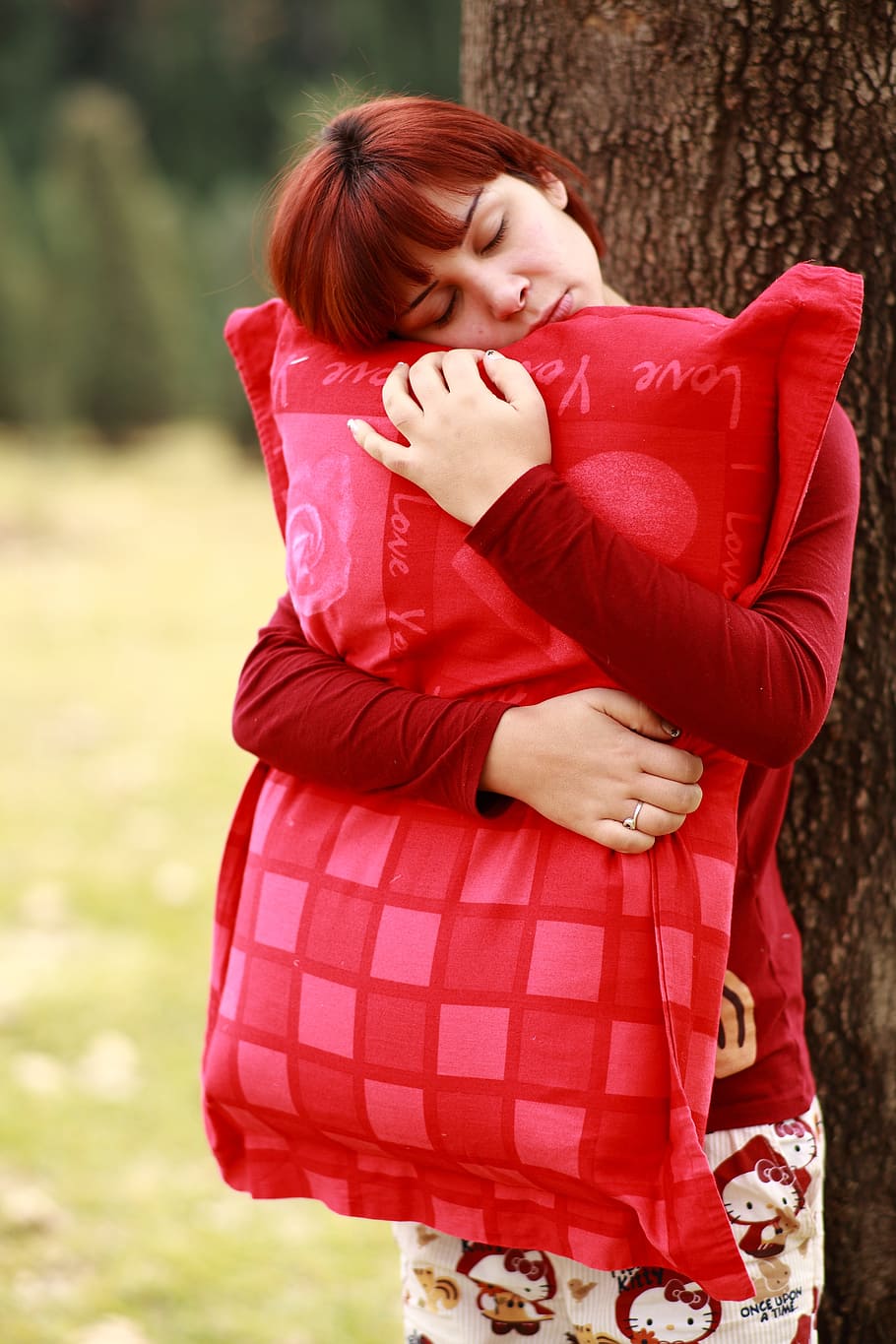 woman hugging red pillow beside tree during daytime, sleep, sleepwalking