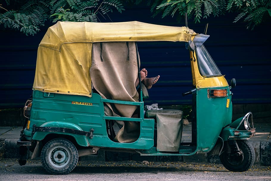 green and yellow auto rickshaw beside green leaves, photography