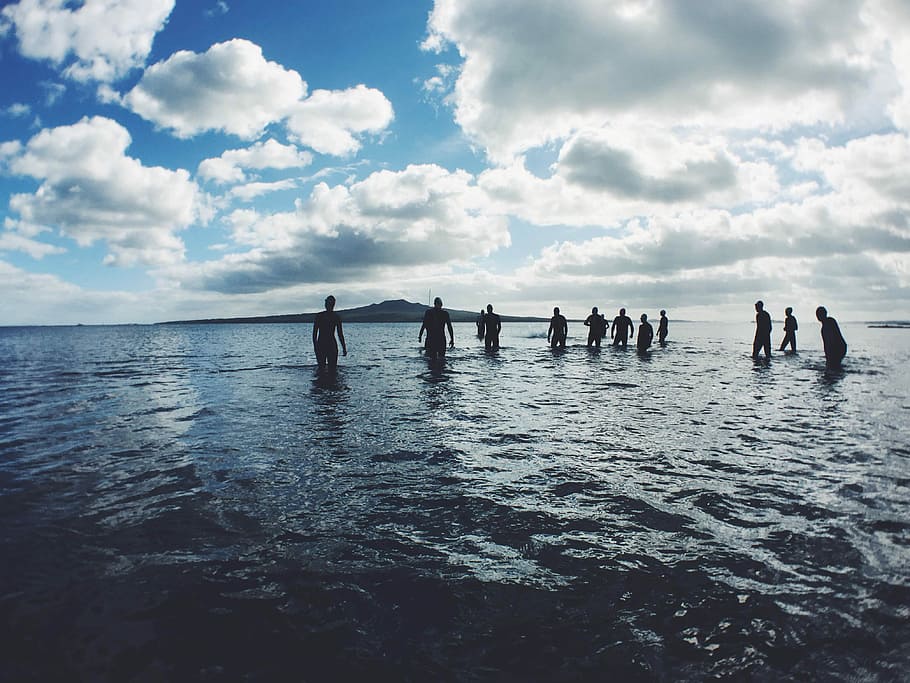 group of people swimming, silhouette of people on body of water under white cloudy sky at daytime HD wallpaper