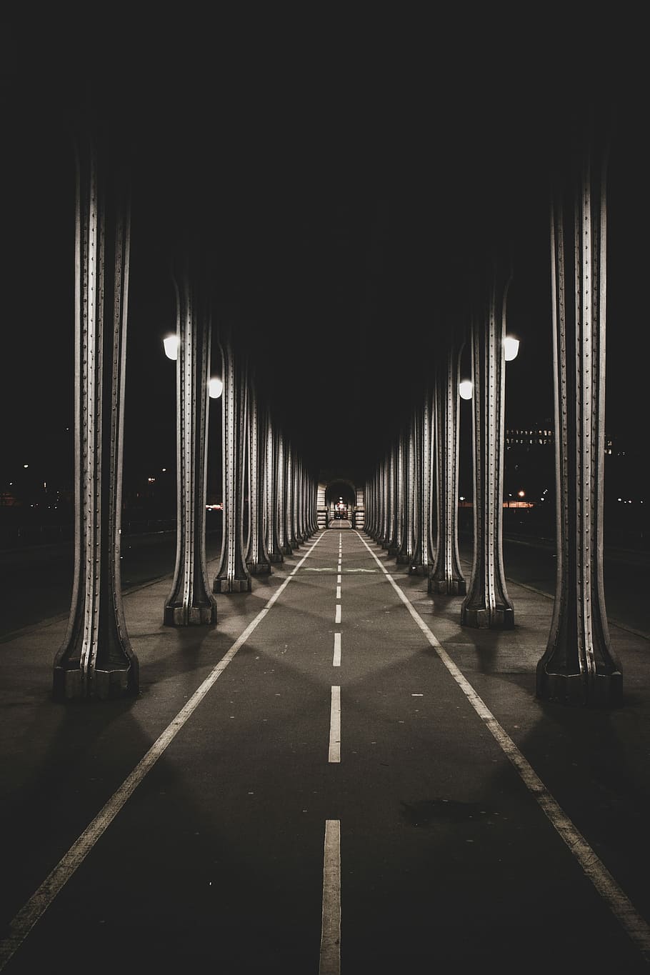 road under gray bridge, empty asphalt roadway during nighttime