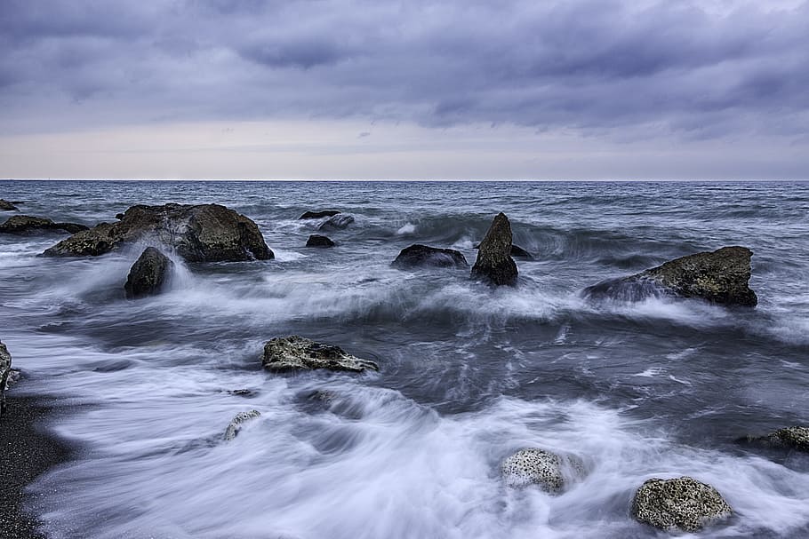 photo of a dancing waves with rocks, seashore with medium rocks and waves under white cloudy sky at daytime HD wallpaper