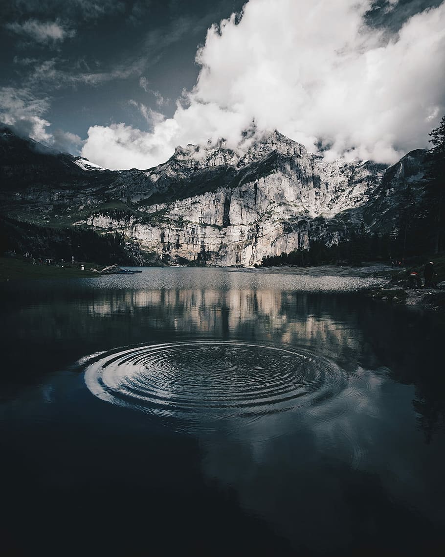 mountain covered by cloud, shallow focus photography of water drop in body of water in front of snowy mountain HD wallpaper