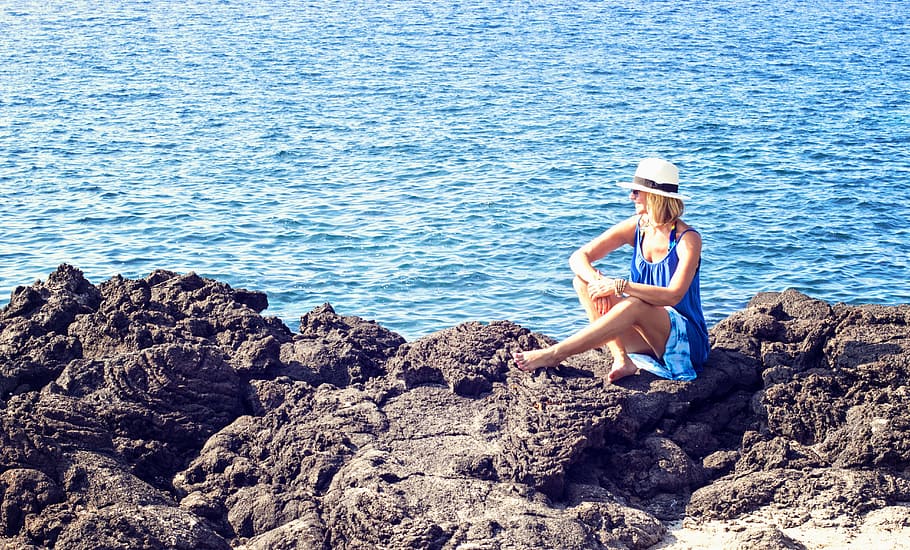 woman in blue scoop-neck sleeveless dress sitting on black rock near ocean at daytime, HD wallpaper