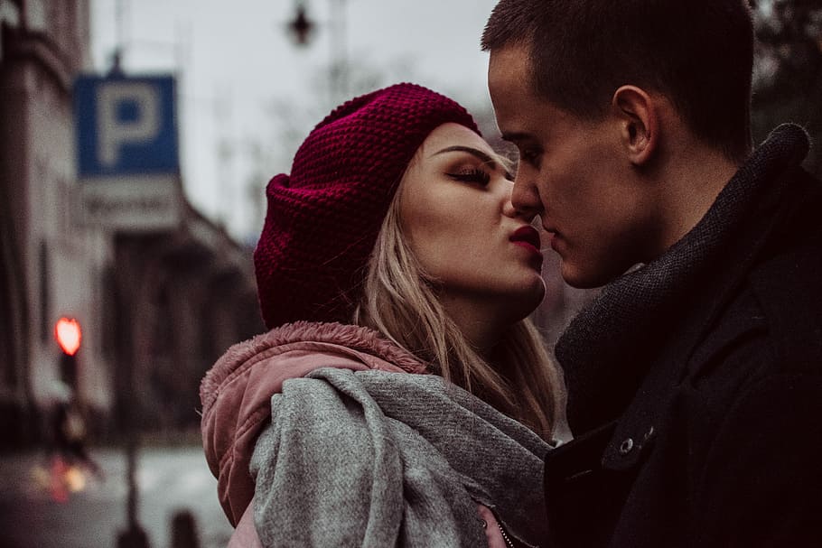 man and woman standing while kissing beside street signage, selective focus photography of kissing man and woman HD wallpaper