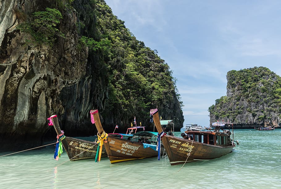 three brown wooden boats dock on shoreline, phi phi island tour