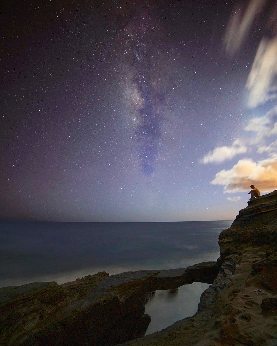 man sitting on rock cliff photo, sky, rocks, night, stars, clouds HD wallpaper