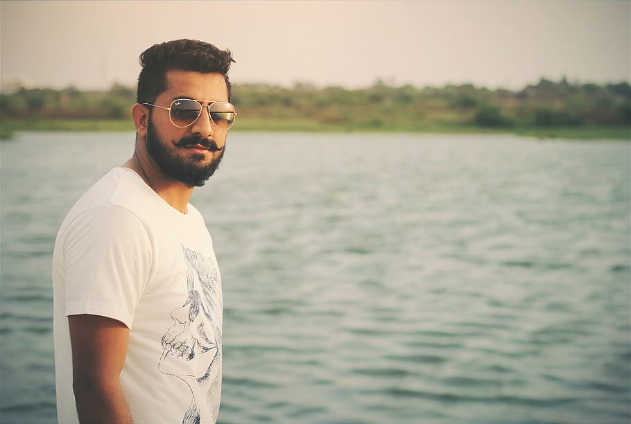 man wearing white crew-neck shirt near body of water at daytime HD wallpaper