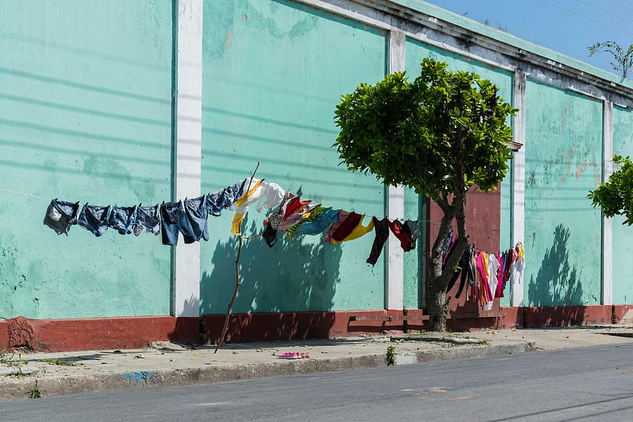 clothe lot hanged on clothesline near tree during daytime, assorted-color clothes lot hanging beside teal building