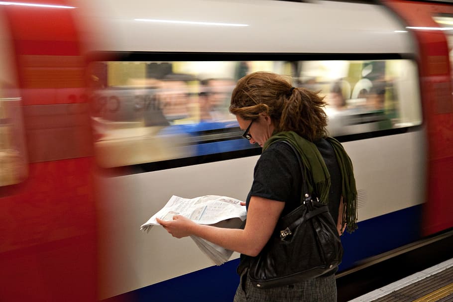 A woman reads the newspaper as she waits for her connection on the London Underground, HD wallpaper