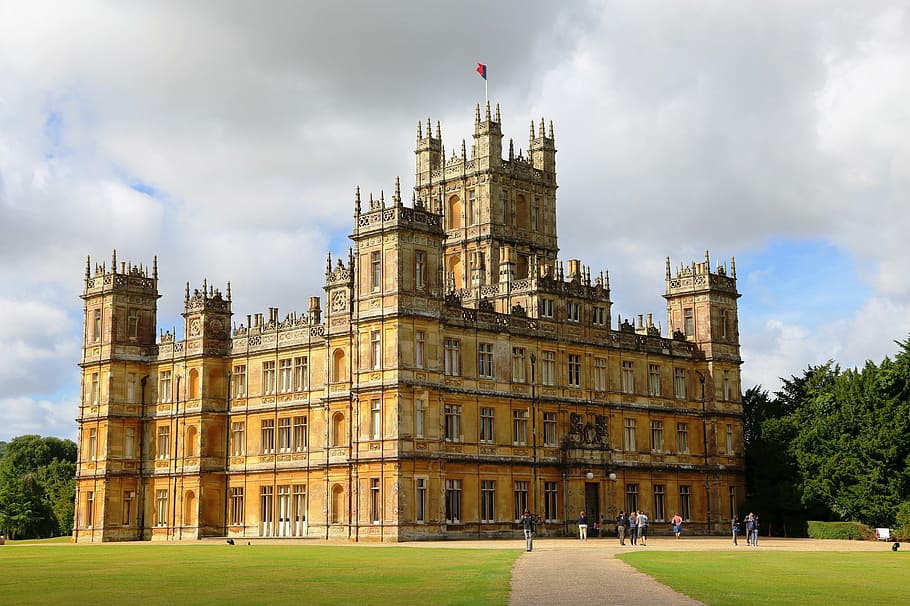 castle with flag on top under white and blue skies, highclere