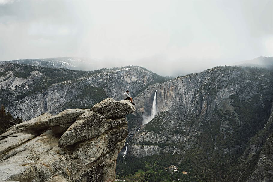 person sitting on mountain cliff, man sitting cliff edge, rock