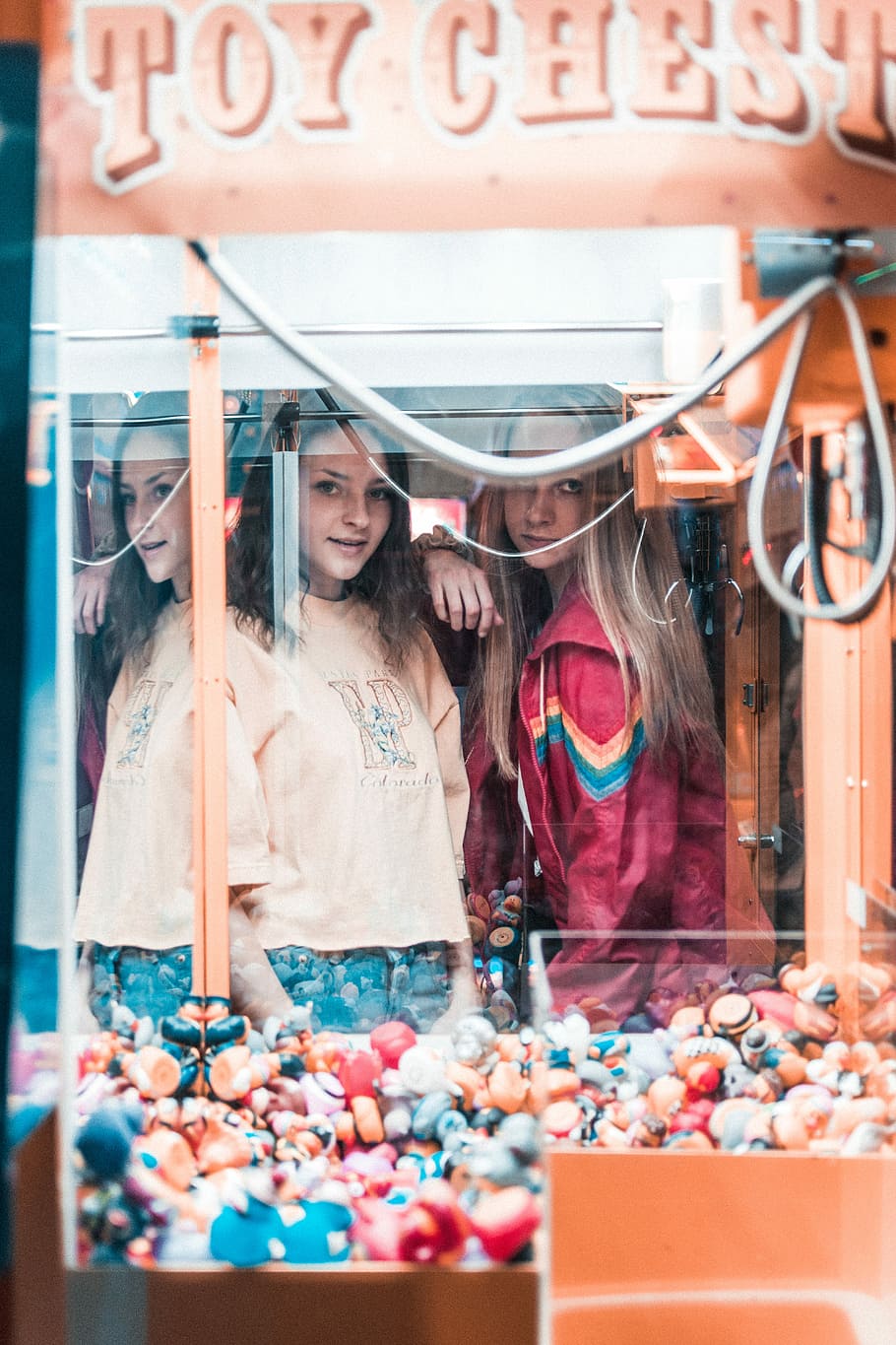 woman playing arcade, reflection of two women on Toy Chest claw machine glass enclosure HD wallpaper