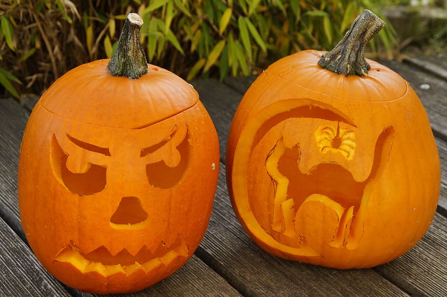two Jack-O-Lanterns on brown wooden surface near green grass