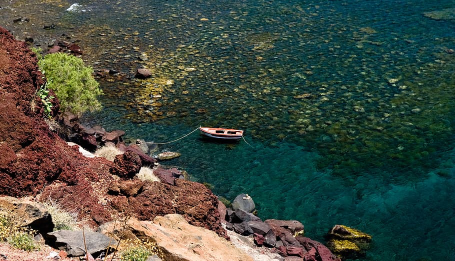 aerial view photography of jon boat beside rock, cliff, mountain