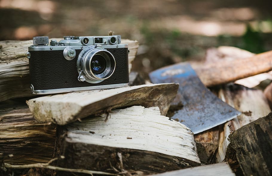 black and gray camera beside axe, selective focus photography of black DSLR camera on firewoods HD wallpaper