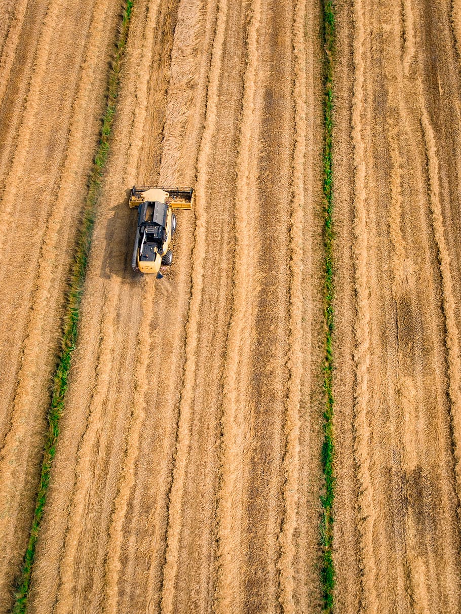aerial photography of yellow cultivator on brown field, yellow and black front loader toy