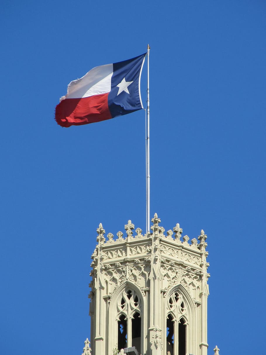 white concrete tower with blue, white, and red flag on top, texas state flag