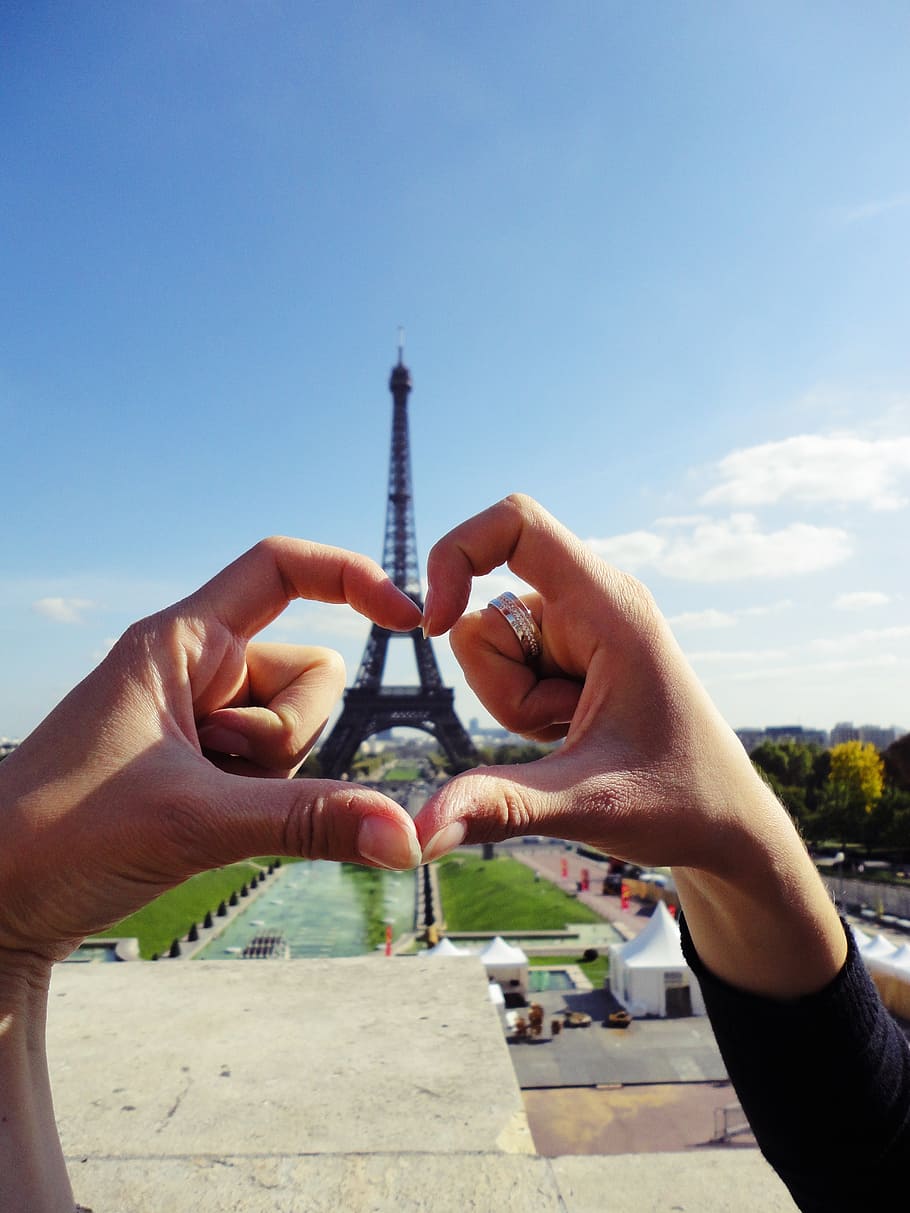 forced perspective photography of couple making heart hand sign during daytime HD wallpaper