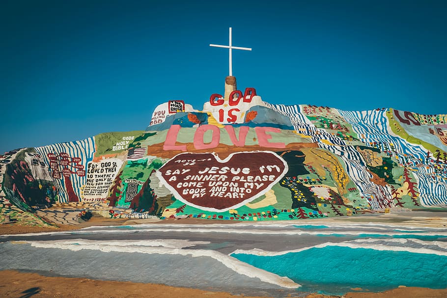 god is love Jesus wall painting during daytime, God if Love hill monument under clear sky