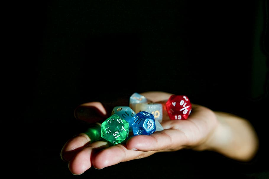 person holding polygonal die, person holding assorted-color playing dies HD wallpaper