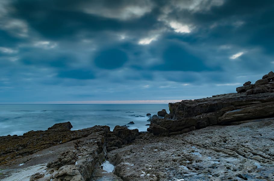 sea near cliff under gray and white cloudy sky, seaside, rocks HD wallpaper