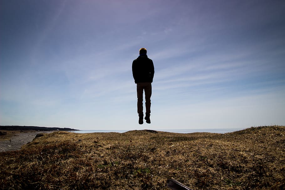man hovering over brown grass, jumping, silhouette, sky, dom HD wallpaper