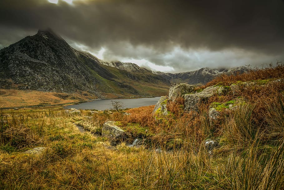 landscape photography of mountain under cloudy sky, mountain beside river HD wallpaper