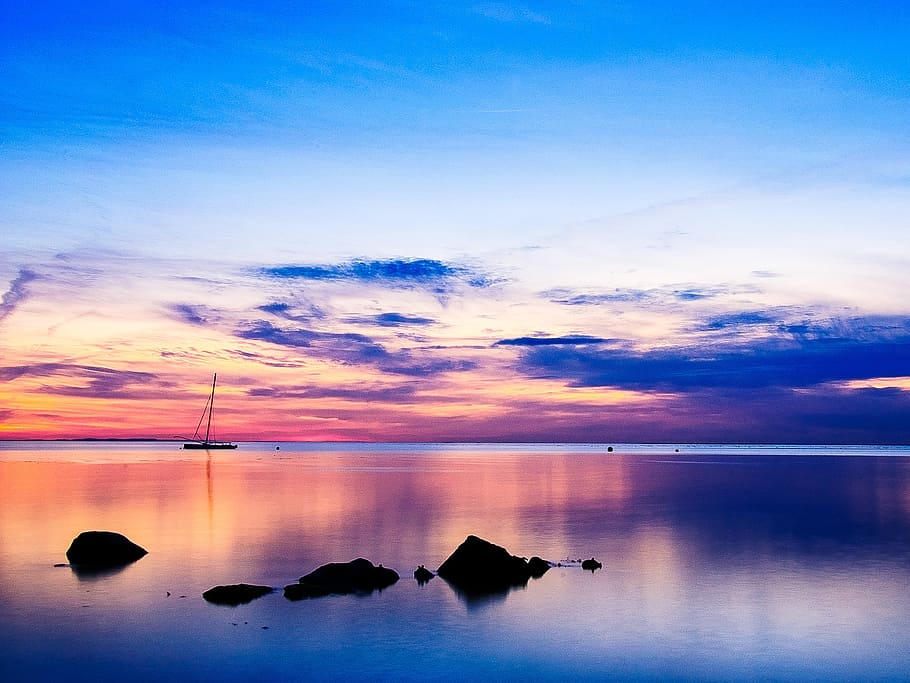 silhouette photo of boat and rock in calm body of water at sunset HD wallpaper