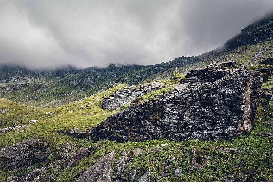 green and brown mountain under cloudy sky, grass covered mountain under gray cloudy sky during daytime HD wallpaper