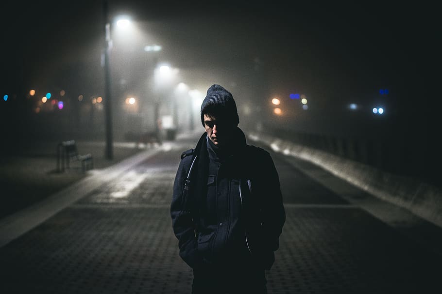 man standing near street lights, man standing on road near road lamp