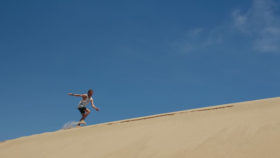 man running on brown sand under blue sky, man running on dessert at daytime HD wallpaper