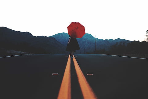 woman walking in the middle of the road with umbrella during day, woman wearing black dress walking on black concrete road top while holding red umbrella during daytime HD wallpaper
