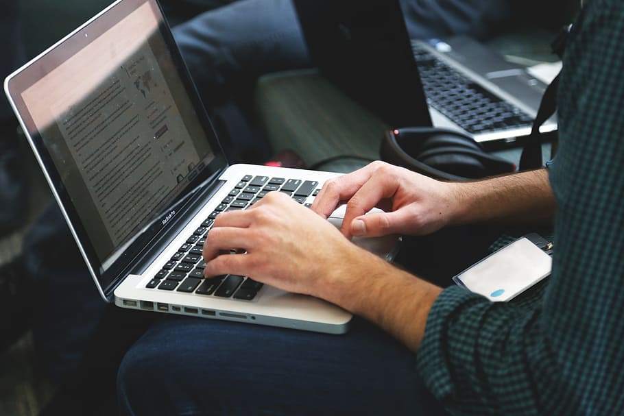 person wearing black and green checked shirt using MacBook Pro HD wallpaper