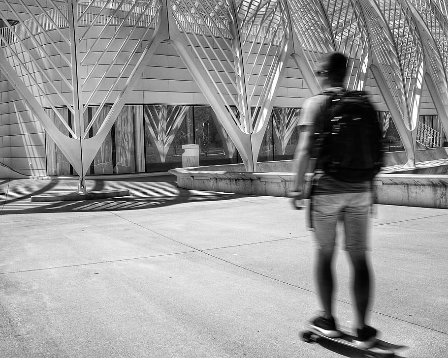 man standing on skateboard, person in white shorts wearing black backpack HD wallpaper