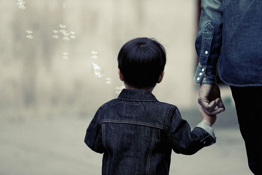 selective focus photography of boy holding hand of her mother