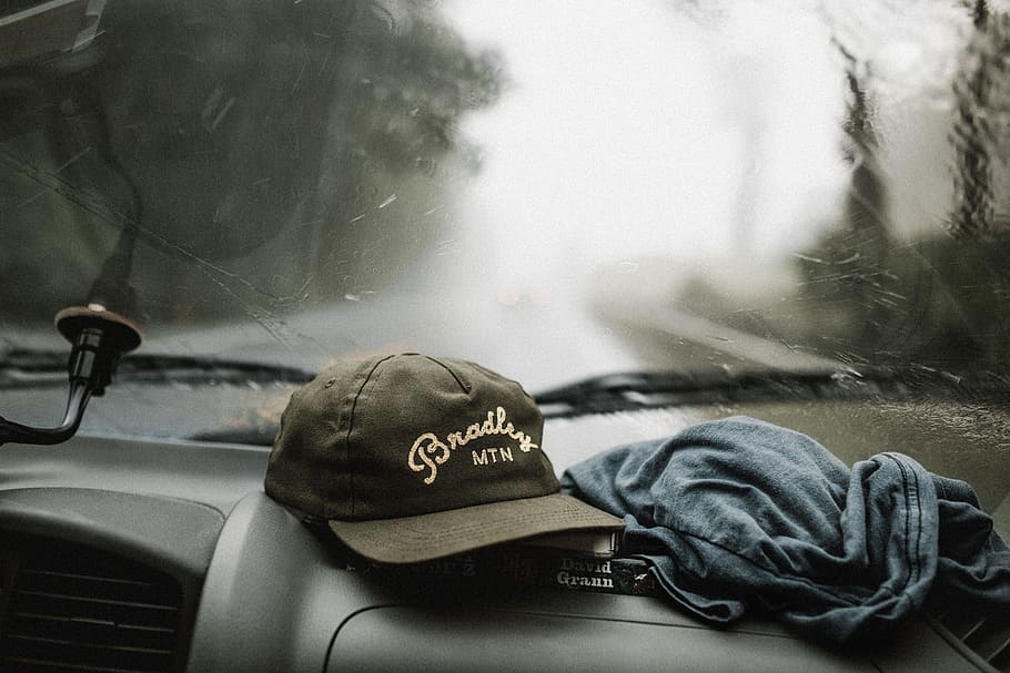 black and white baseball cap near grey shirt on top of glove compartment inside car, tilt-shift photography of cap and shirt HD wallpaper