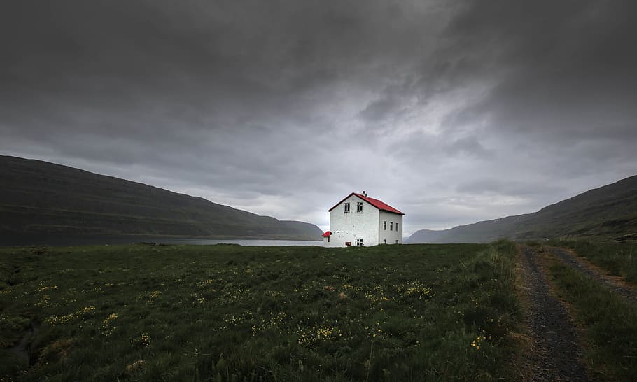 architectural photography of red and white house, white concrete house near mountain under the cloudy sky