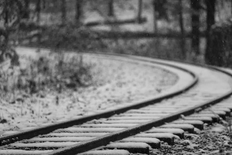 selective focus photography of black metal railroad covered with snow, grayscale photography of train rails