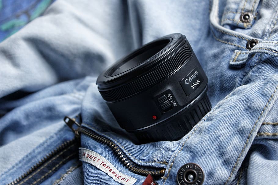 black Canon 50mm lens, black Canon 50 mm camera lens on blue denim bottoms HD wallpaper