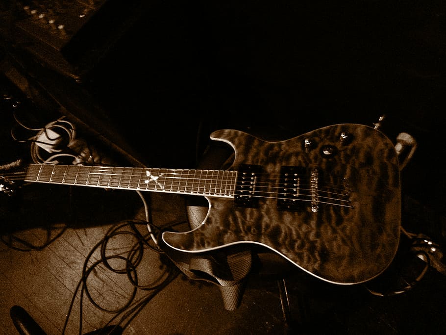 brown and black electric guitar on brown surface, monochrome