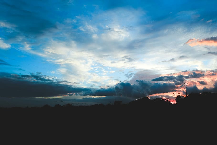 silhouette of mountain under gray clouds at golden hour, skies and clouds during daytime HD wallpaper