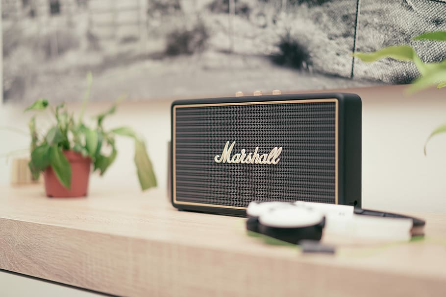 black Marshall Bluetooth speaker on top of brown table, shallow focus photography black Marshall speaker on wooden board