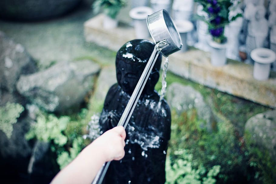 person watering figurine during daytime, person washing black statue HD wallpaper