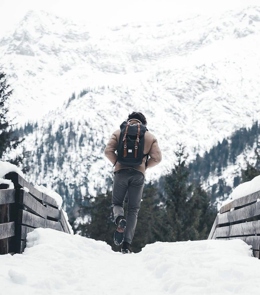 person walking on snowy road, person walking towards snow covered mountain HD wallpaper