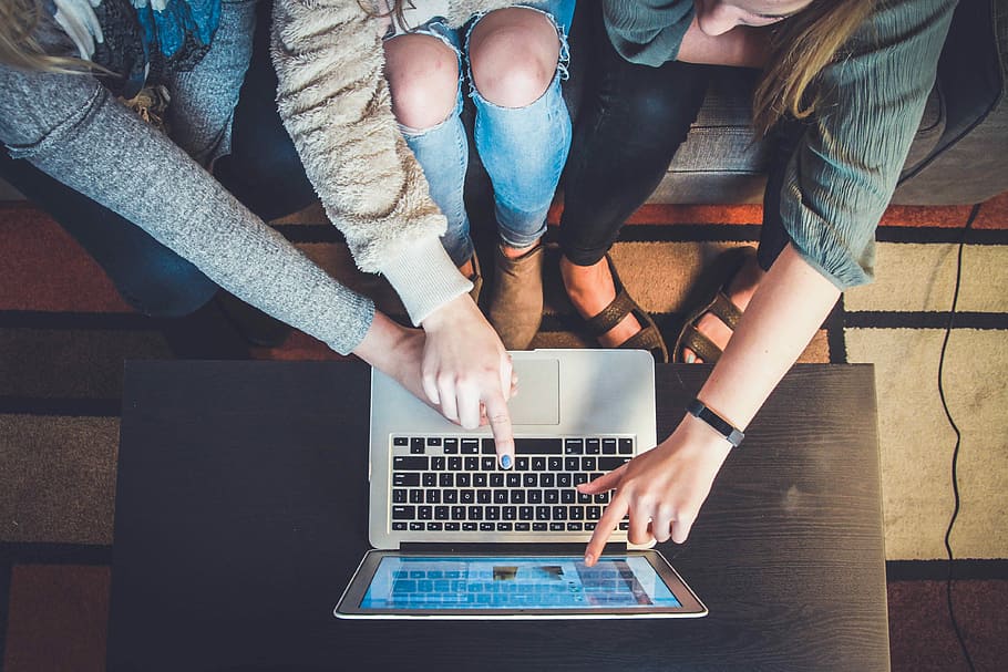 three person pointing the silver laptop computer, three person touching MacBook Air on table HD wallpaper