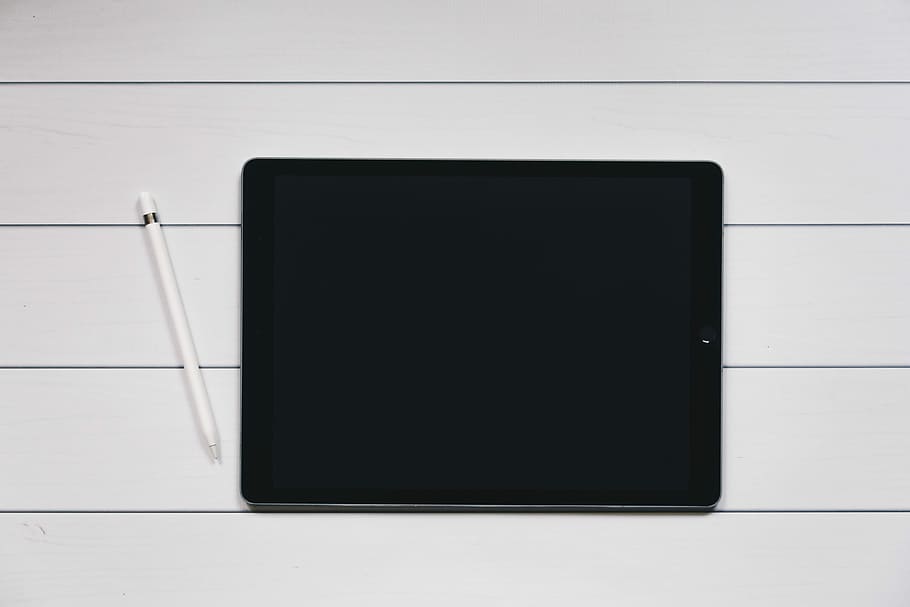 space gray iPad with Apple Pencil with white and black pinstriped background, turned off iPad with Apple Pencil