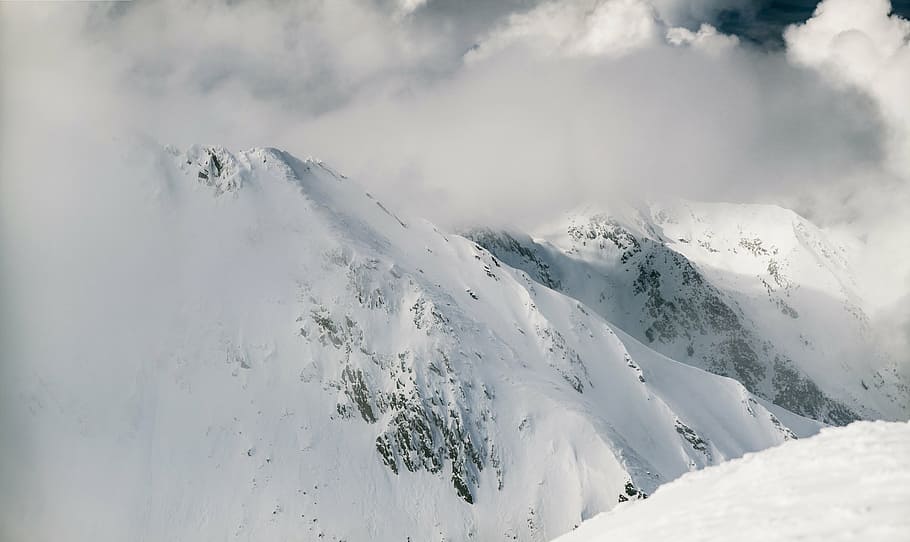 snow covered mountain surrounded by fogs under white cloudy sky at daytime HD wallpaper