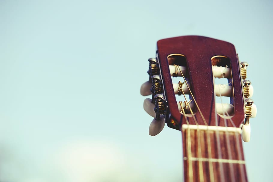 closeup photo of brown classical guitar headstock, sky, neck