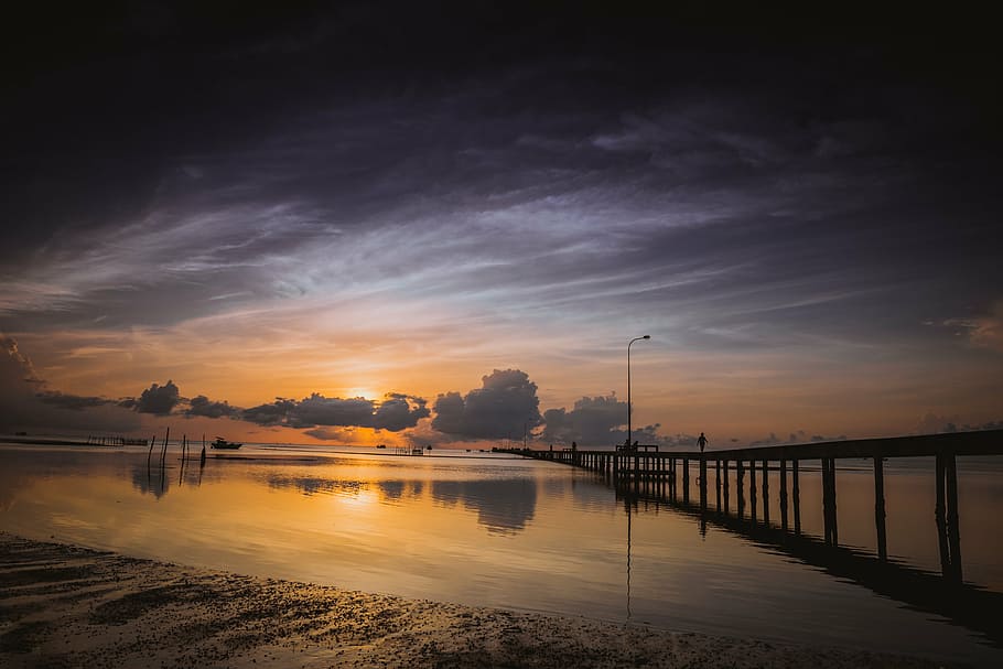 sunset on body of water with dock, ham ninh, phu quoc, vietnam